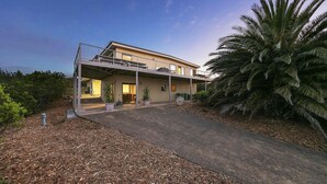 A modern two-story house with a covered patio, a driveway, and a large palm tree. - Last Minute Discount Available! Moonah Ridge Residence - Perfect for groups. (St Andrews Beach)