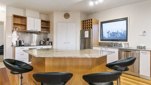 A modern kitchen with a central island, bar stools, a refrigerator, and a large window. - Last Minute Discount Available! Moonah Ridge Residence - Perfect for groups. (St Andrews Beach)