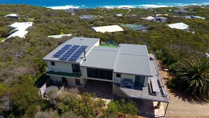 A modern house with solar panels, surrounded by dense vegetation and a coastal view. - Last Minute Discount Available! Moonah Ridge Residence - Perfect for groups. (St Andrews Beach)