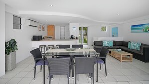 A modern living space with a dining area, kitchen, and seating area. - Ocean View Villa - 02  (Hamilton Island)