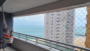 Un balcón con vista al mar, paredes con azulejos y una hamaca.