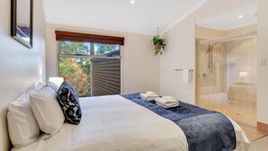 Un dormitorio con cama, ventana, zona de ducha y una planta colgante.