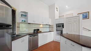 Una cocina moderna con armarios blancos, electrodomésticos de acero inoxidable y piso de baldosas.
