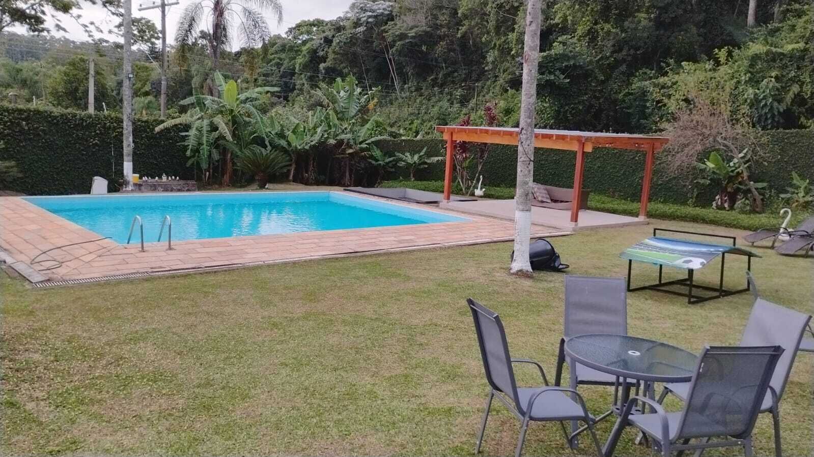 A backyard with a swimming pool, a wooden pergola, and outdoor seating.