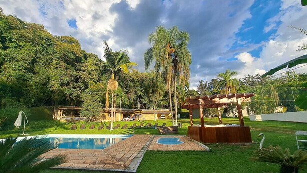 Un jardín trasero con piscina, un pérgola y un pabellón.