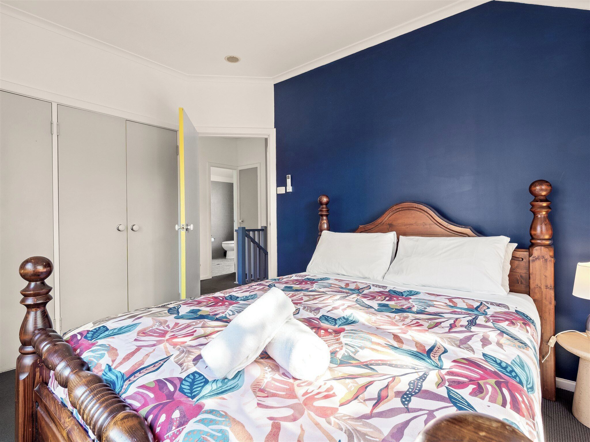 Een slaapkamer met een bed, een kledingkast en een badkamer die door een open deur zichtbaar is.