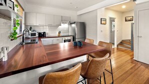 A modern kitchen with white cabinets, a wooden countertop, and a stainless steel refrigerator. - Cosy Corner | Margaret River (Margaret River)
