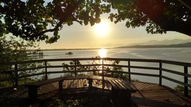 A wooden deck with a view of a lake and mountains in the background. - Furnished apartment on Itaúna beach, a popular spot for international surfing. (Saquarema)