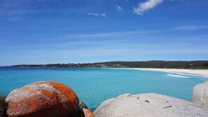 A coastal landscape with clear blue waters, a sandy beach, and rocky outcrops. - BAY OF FIRES ECO HUT Binalong Bay - Off Grid Experience (Binalong Bay)