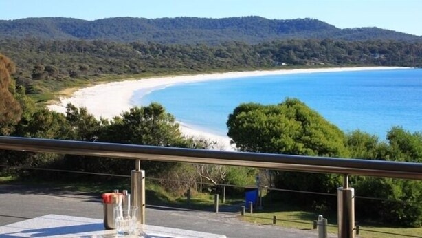 A coastal view with a beach, forested hills, and a clear sky. - BAY OF FIRES ECO HUT Binalong Bay - Off Grid Experience (Binalong Bay)