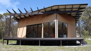 A modern, single-story building with a flat roof and large windows. - BAY OF FIRES ECO HUT Binalong Bay - Off Grid Experience (Binalong Bay)