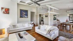 Un salón amplio con un sofá blanco, una mesa de comedor y una cocina al fondo.