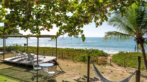 A beachside patio with a pergola, lounge chairs, and a hammock. - Vila do Outeiro em frente a praça da igreja (Porto Seguro)