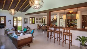 A spacious living area with a high ceiling, wooden beams, and a dining area with bar stools. - Vila do Outeiro em frente a praça da igreja (Porto Seguro)