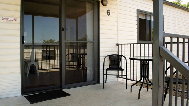 Un bâtiment doté d’une entrée avec une porte-fenêtre coulissante, d’un petit espace extérieur aménagé avec une table et des chaises, et d’un chiffre « 6 » peint sur le mur.