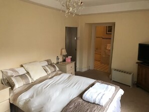 A hotel room with a bed, bedside table, lamp, and a television. - The Carew Arms (Taunton)