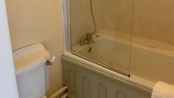 Un bany amb dutxa de vidre, un vàter i un quadre al mur.
