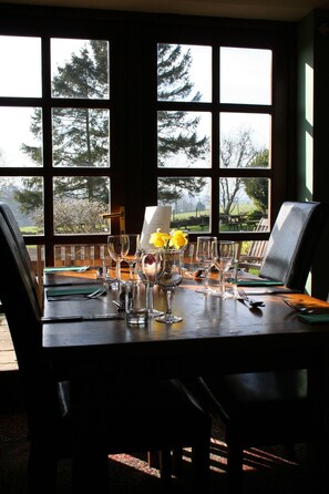 A dining table set with wine glasses, a vase with flowers, and a menu. - The Carew Arms (Taunton)