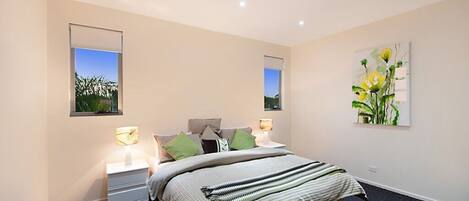 A bedroom with a bed, bedside tables, and a painting on the wall.