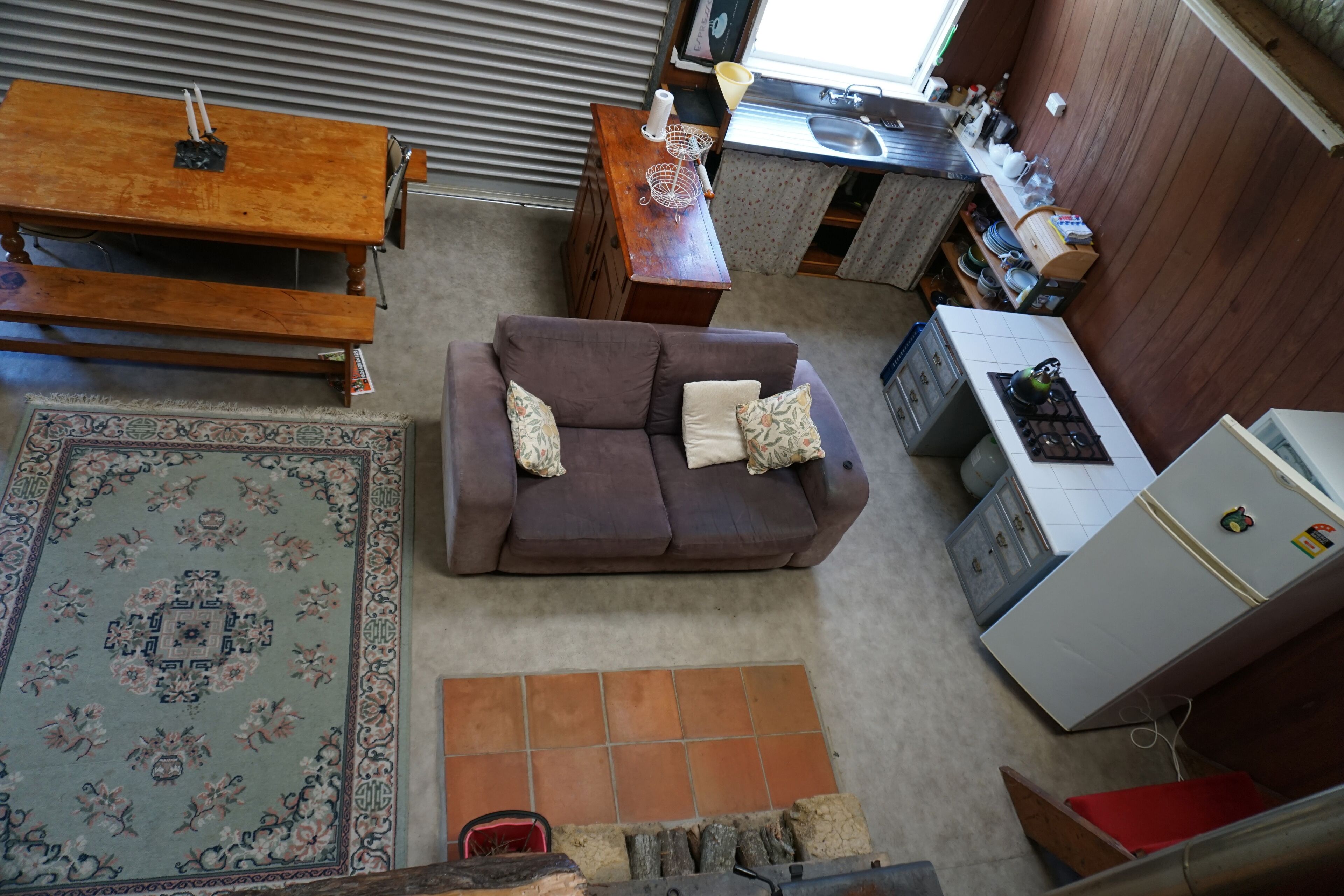 A compact living space with a sofa, a dining table, a kitchen area, and a patterned rug.