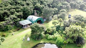 Vue aérienne d’une propriété comprenant un bâtiment doté d’un toit végétalisé, un étang et une végétation luxuriante environnante.