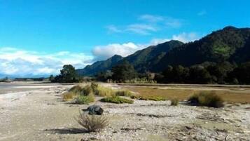 A coastal landscape with a beach, rocky terrain, and mountains in the background.