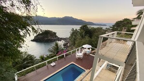 Área da piscina com vista para o mar e montanhas.