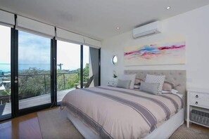 A bedroom with a large bed, a view of the outdoors, and a modern design.