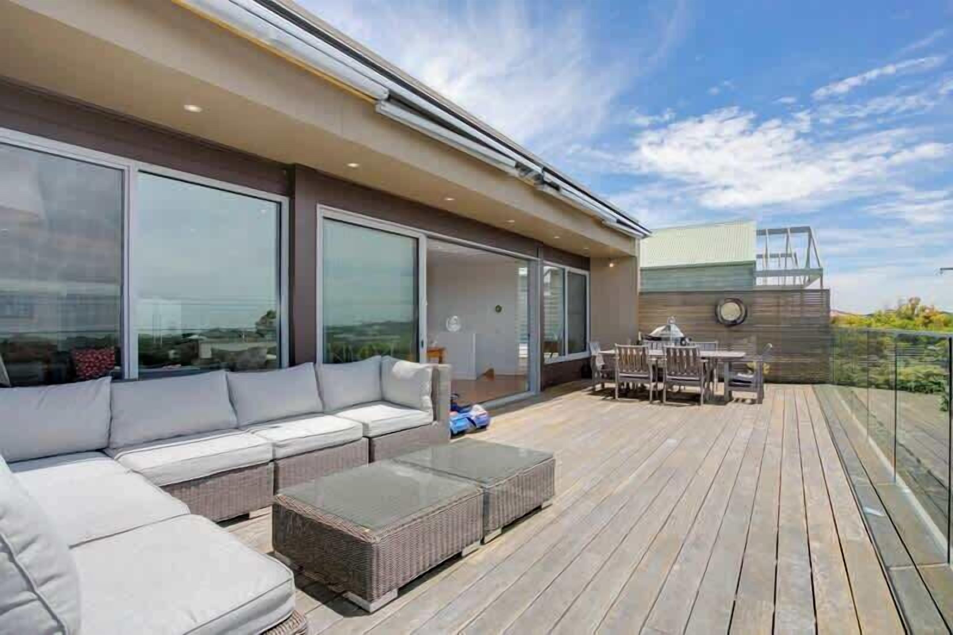 Eine moderne Terrassenanlage mit einer Couch, einem Esstisch und Stühlen.