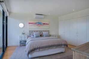 A bedroom with a bed, bedside tables, a wardrobe, and a large window.