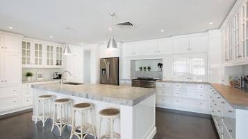 A modern kitchen with white cabinetry, a central island with stools, stainless steel appliances, and pendant lighting.