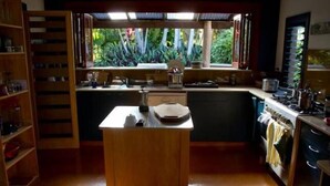 A compact kitchen with a central island, a window with a view of greenery, and a built-in oven. - The Rosebank Farmhouse (Rosebank)