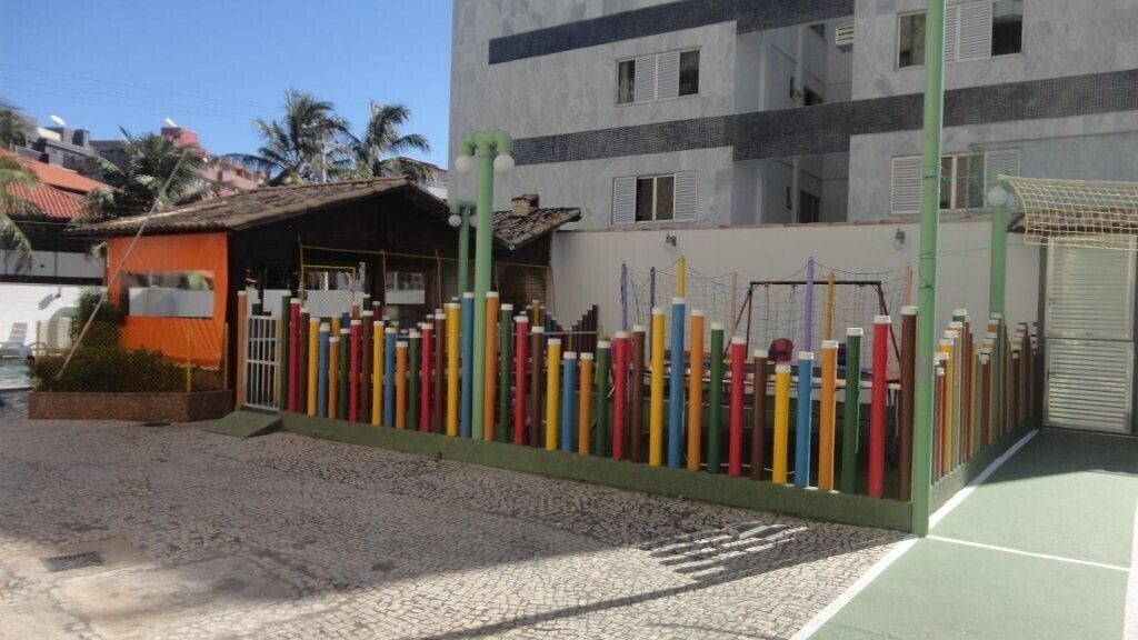 Une clôture aux couleurs vives, ornée de divers objets, un bâtiment avec un toit en tuiles et une zone pavée.