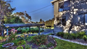 A modern house with a well-maintained garden, a patio, and a clear sky.