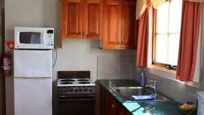 A compact kitchen with a microwave, refrigerator, stove, and sink. - Hatcher's Manor Richmond - Farmhouse (Richmond TAS)