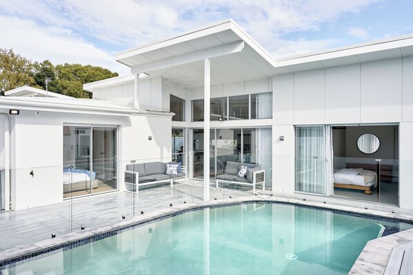 Ein modernes Haus mit Schwimmbad, großen Fenstern und einem Balkon.
