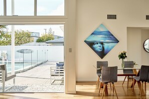 Ein modernes Wohnzimmer mit einem Glastisch, grauen Stühlen und einem großen, abstrakten Gemälde an der Wand.