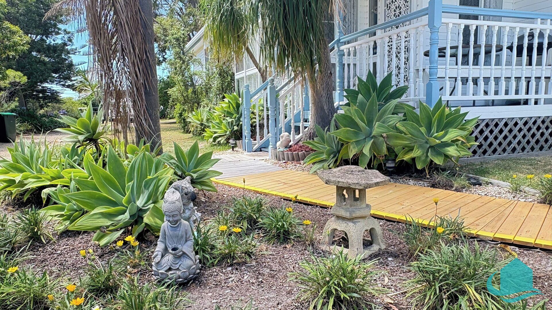 Ein Garten mit einer Holzterrasse, einer Buddha-Statue und einem Steinlaternen.