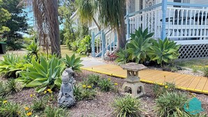 A garden with a wooden deck, a Buddha statue, and a stone lantern. - Bromyard Lakeside Cottage - access to waterfront (Swansea)