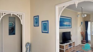 A living room with a television, framed artwork, and a decorative piece on the wall. - Bromyard Lakeside Cottage - access to waterfront (Swansea)