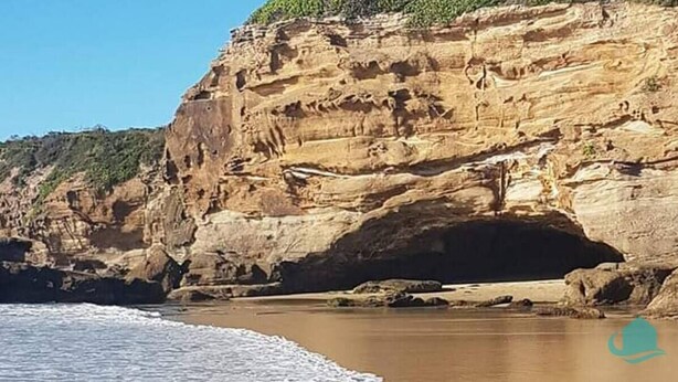 A coastal cliff with a natural cave entrance, a sandy beach, and a clear blue sky. - Bromyard Lakeside Cottage - access to waterfront (Swansea)
