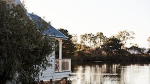 Una casa sul lago con un molo che si protende sull'acqua, circondata da alberi e un cielo sereno.