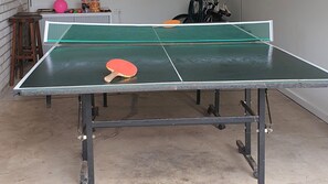 A ping pong table with a net in a room with a concrete floor. - Werri Escape - walk to the beach (Gerringong)