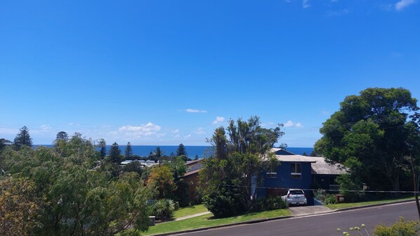 A residential area with houses, a clear blue sky, and a view of the ocean. - Werri Escape - walk to the beach (Gerringong)