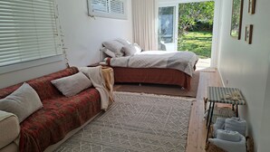 A bedroom with a bed, a sofa, and a small table. - Werri Escape - walk to the beach (Gerringong)