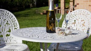 A table with a bottle of champagne and two glasses on a white outdoor table.