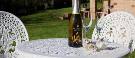 Una mesa blanca al aire libre con una botella de champán y dos copas.