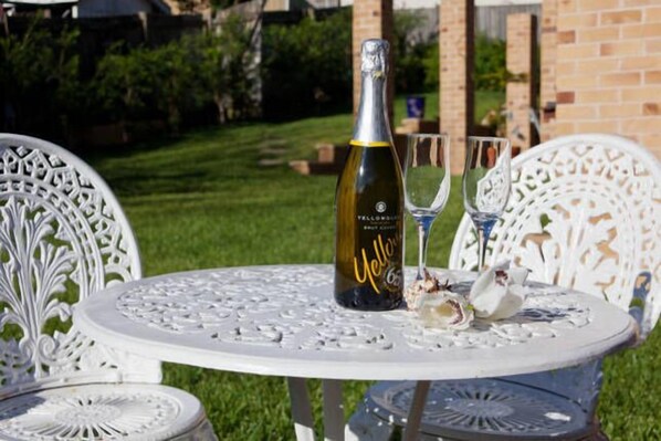 A table with a bottle of champagne and two glasses on a white outdoor table.