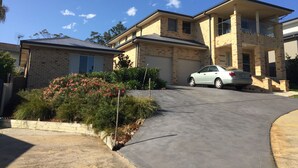 A two-story house with a garage, a driveway, and a car parked in the driveway.