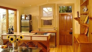 A compact kitchen with wooden cabinetry, a built-in oven, and a window above the sink. - Bishops Garden Spa Suite (North Adelaide)